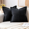 Black striped corduroy lumbar support pillow cushion resting on a light-colored sofa.