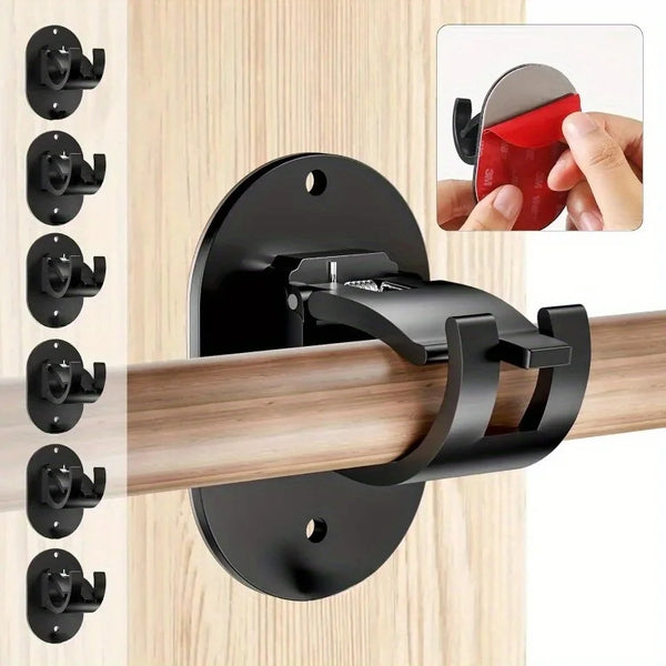 Black heavy duty self-adhesive curtain rod holders with a red grip shown mounted on a wooden surface.
