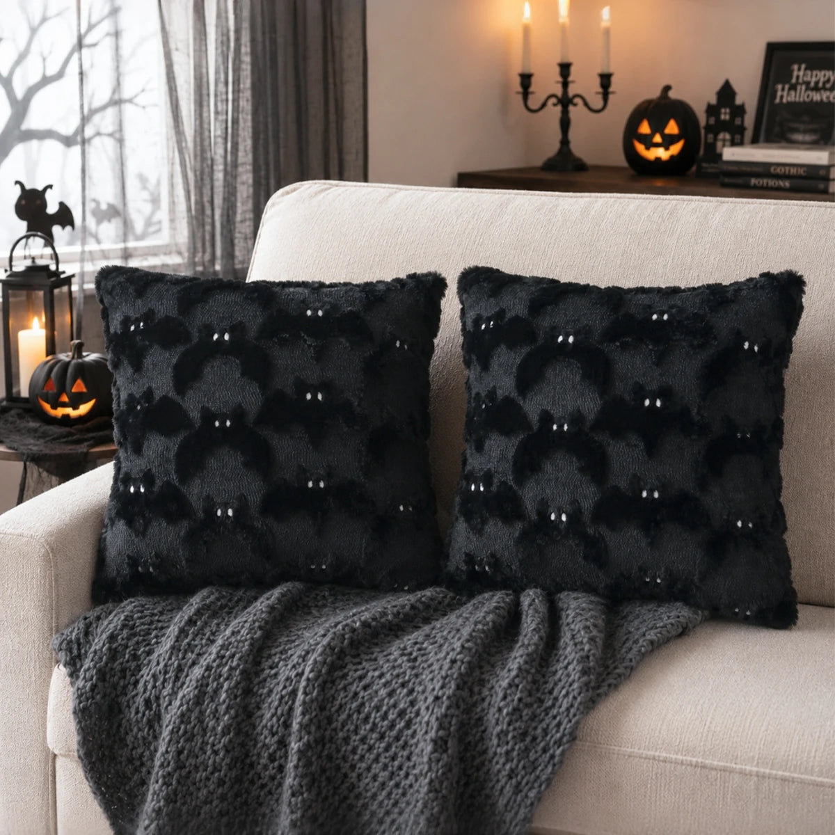 A dark gray bat plush cushion cover decorated with subtle Halloween patterns on a white sofa.