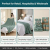A green pure cotton gauze throw blanket draped over a white bed in a hotel setting.