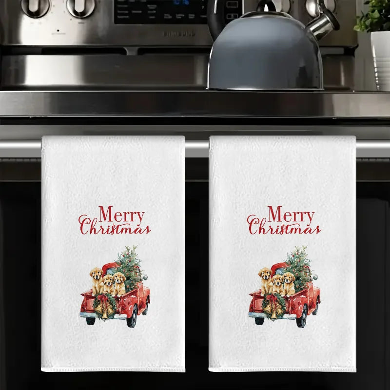A set of white kitchen towels featuring a Christmas greeting and an illustration of golden dogs in a red vintage truck.