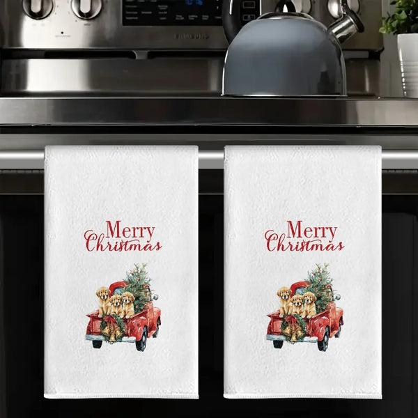 A set of white kitchen towels featuring a Christmas greeting and an illustration of golden dogs in a red vintage truck.