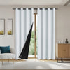 White blackout curtains hanging on a rod in a room with a wooden door and framed art.