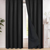 A floor-length black blackout curtain hanging in a window frame.