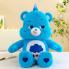 A blue Care Bears Rainbow Bear plush toy with a white chest cloud and heart details sitting on a white surface.
