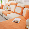 An orange leaf jacquard stretch sofa cover with white cushions and anti-slip backing.