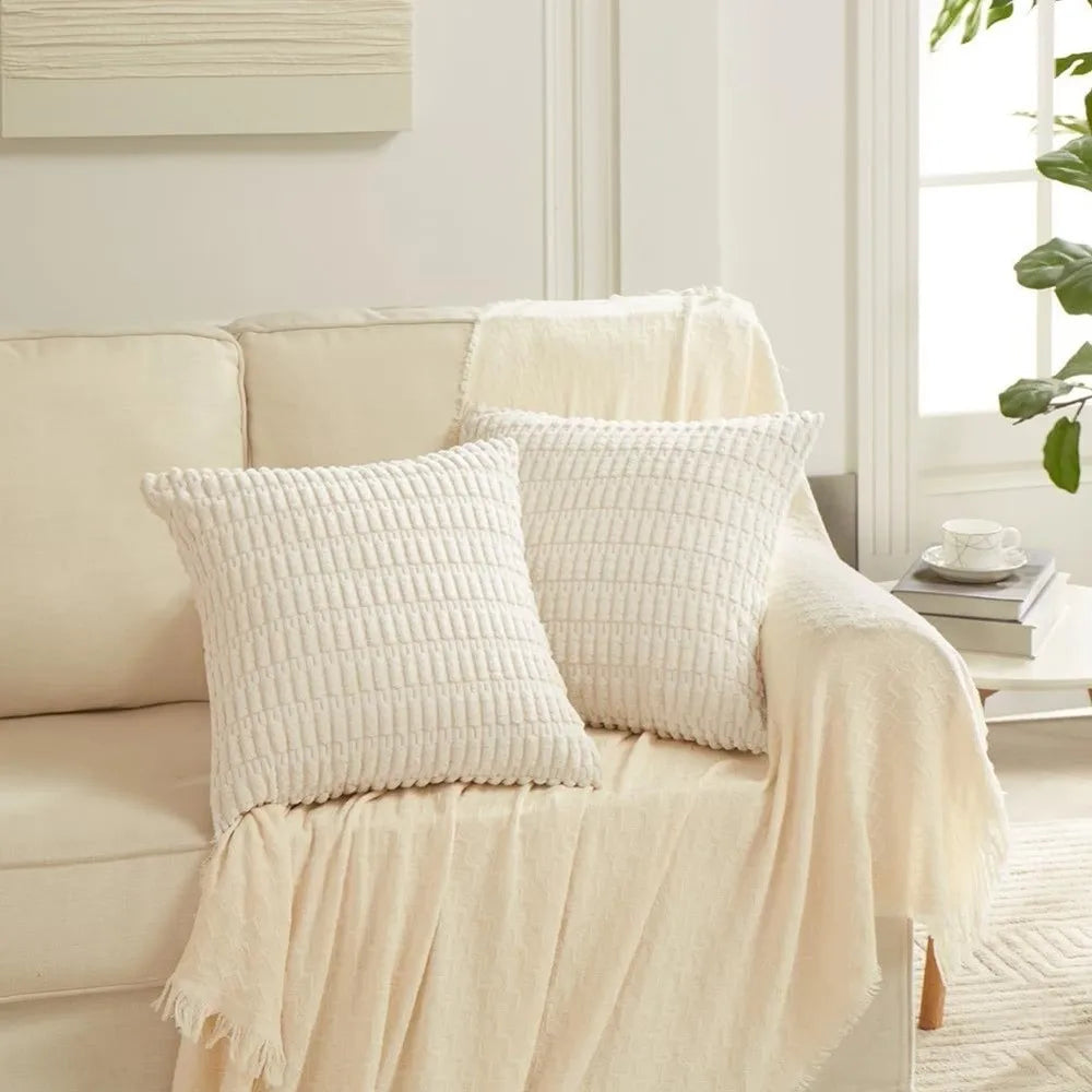 Two white textured striped velvet throw pillow covers draped on a light-colored sofa.