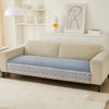 A beige sofa with a blue quilted cover featuring a white lace trim, displayed in a bright living room.