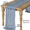 A grey semi-sheer gauze table runner draped over a wooden table, showing its length and texture.