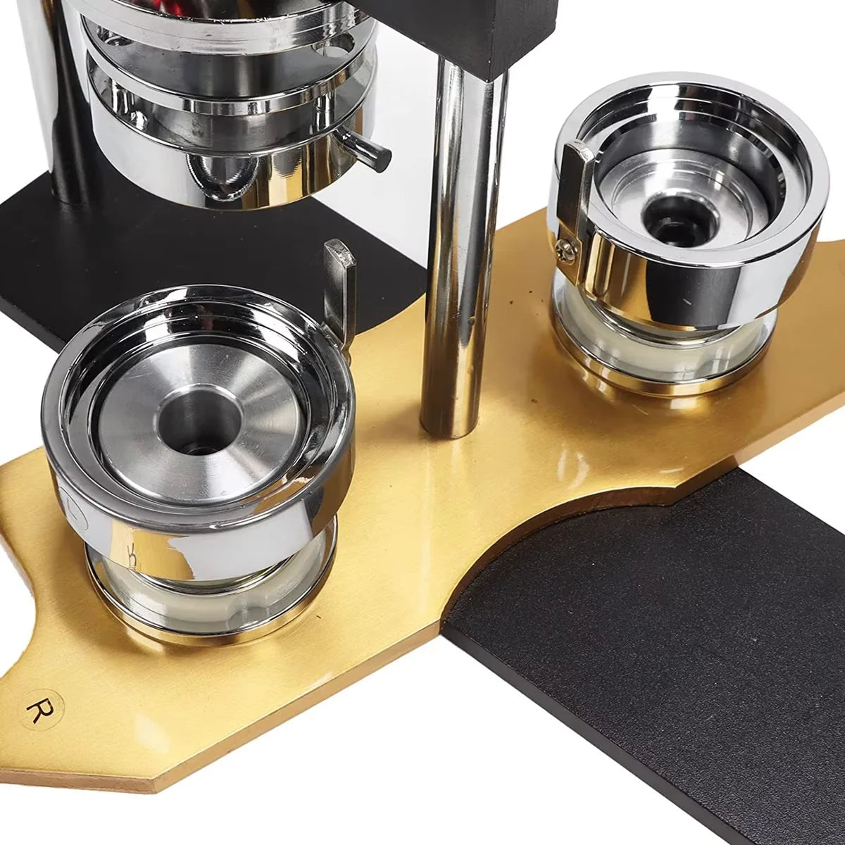 A professional button making machine kit showing various metal components and a gold-colored base.