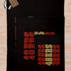 A black knitted throw blanket with colorful lettering is displayed on a light wooden surface.