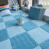 A light blue plush play mat with checkered tiles, featuring soft toys and cushions.