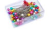 Assortment of decorative sewing and pinning needles in various bright colors like pink, yellow, blue, and red.