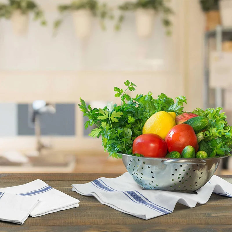A bowl filled with fresh herbs and vegetables on a wooden table with a cloth napkin.