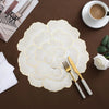 Gold plated peony coasters on a dark brown surface with a white napkin and a cup of coffee.