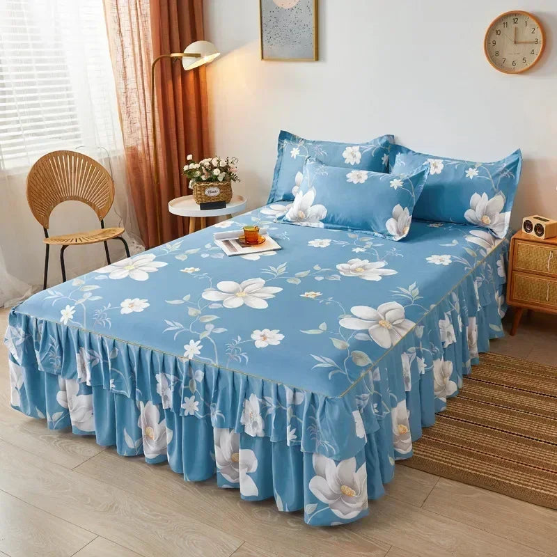 A light blue floral printed bed skirt covering a bed in a bedroom setting.