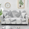 A gray and white patterned elastic sofa cover protector displayed on a light gray floor.