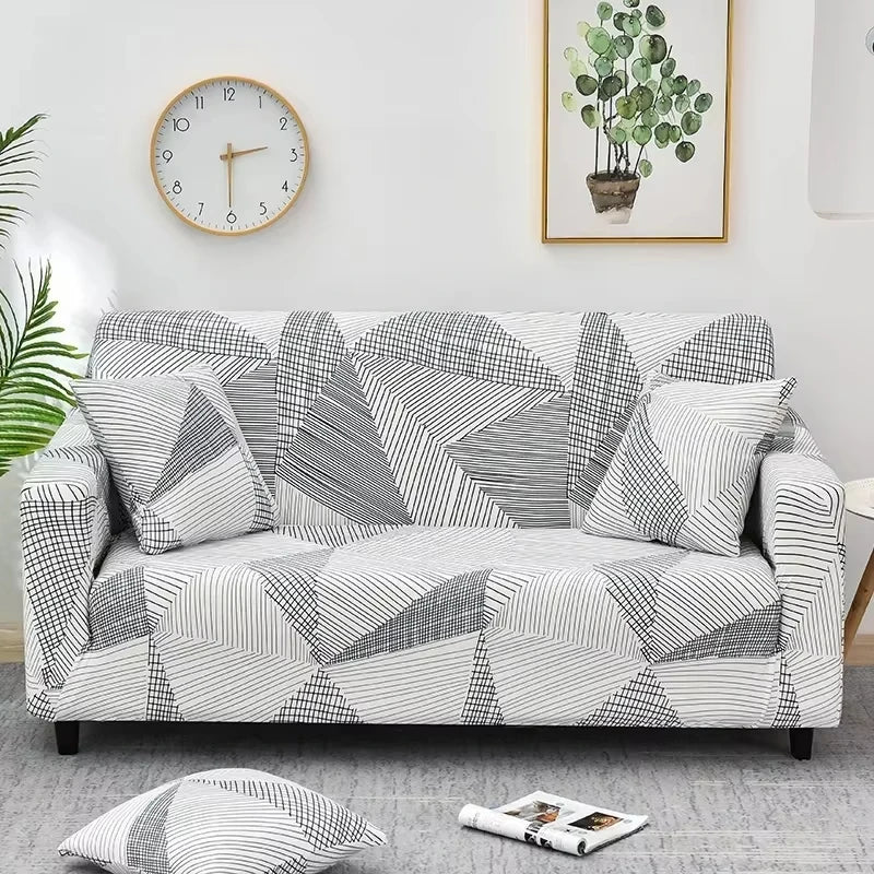 A gray and white patterned elastic sofa cover protector displayed on a light gray floor.