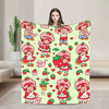 A young woman holds up a pink strawberry shortcake plush throw blanket featuring cute characters and strawberries.