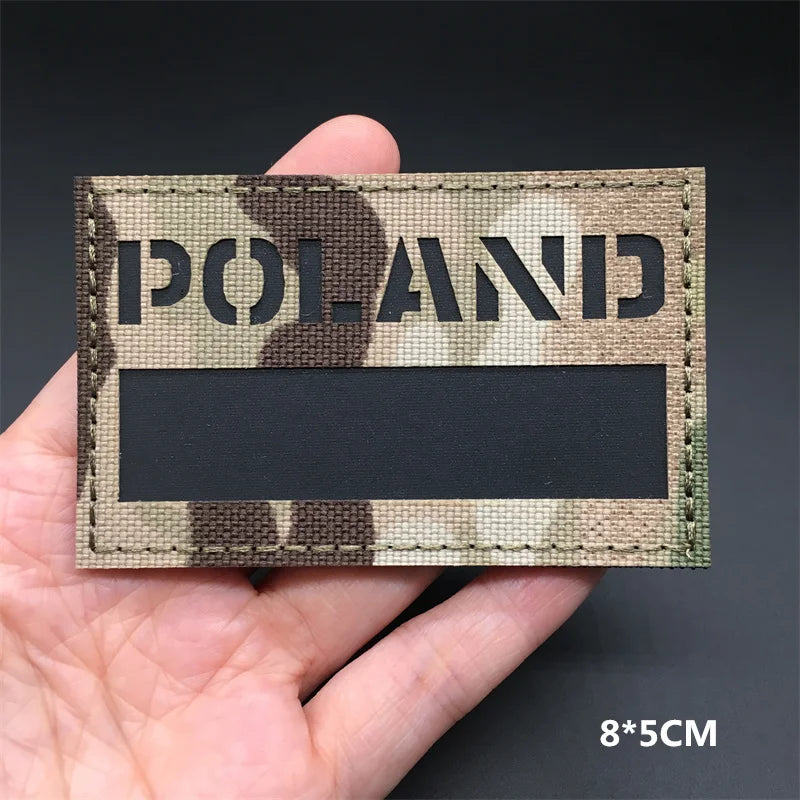 A rectangular tactical patch featuring a camouflage pattern with the word POLAND in dark lettering.