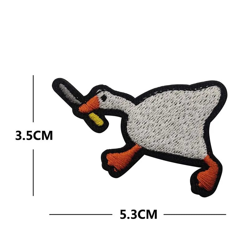 A black and white embroidery patch of a duck with an orange beak and feet.