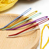 A collection of 20 aluminum knitting needles and sewing pins in various colors laid out on a wooden surface.