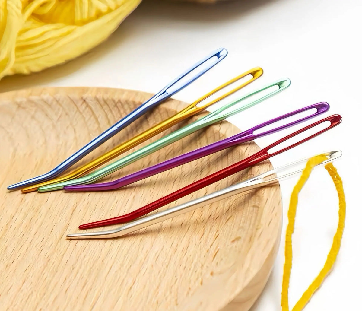 A collection of 20 aluminum knitting needles and sewing pins in various colors laid out on a wooden surface.