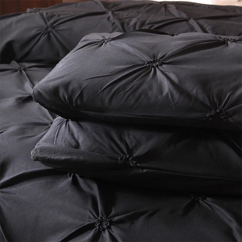 A stack of black velvet pillows and bedding fabric showing a soft, luxurious texture.