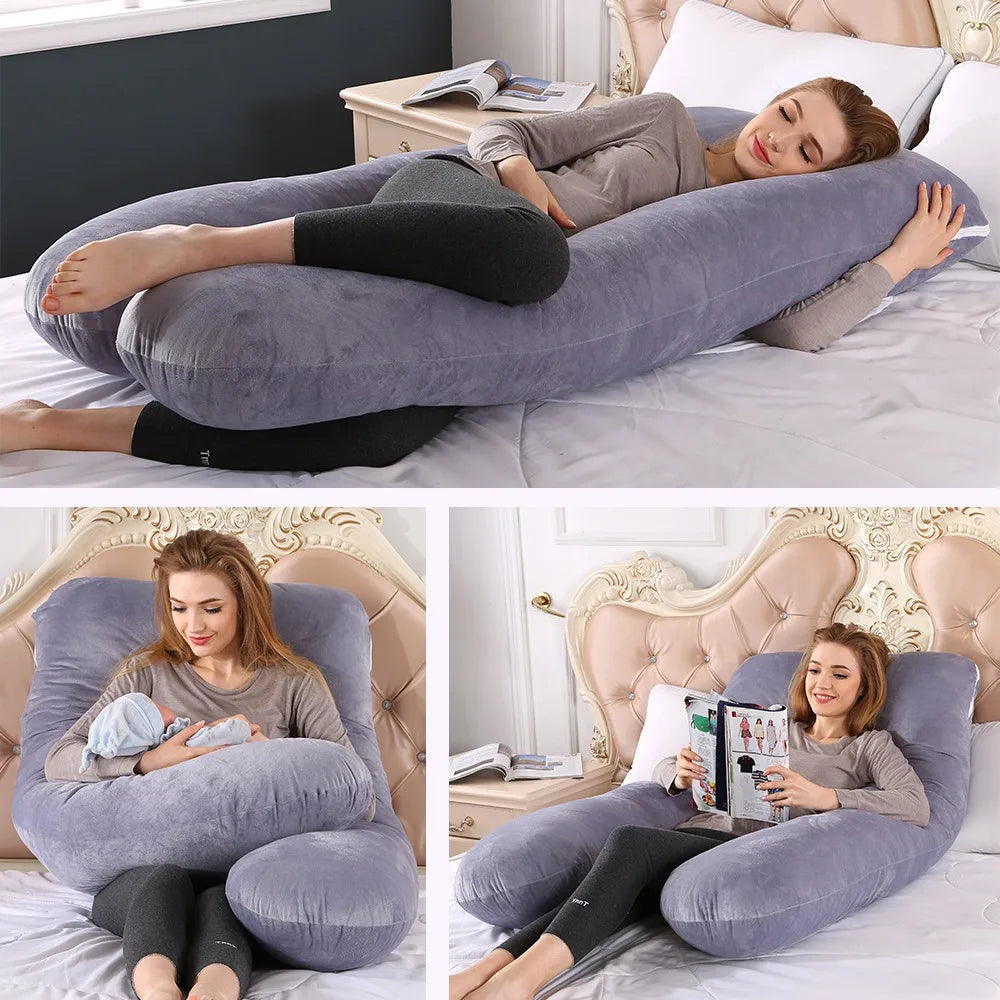 A woman rests comfortably on a gray U-shaped maternity body pillow on a bed.