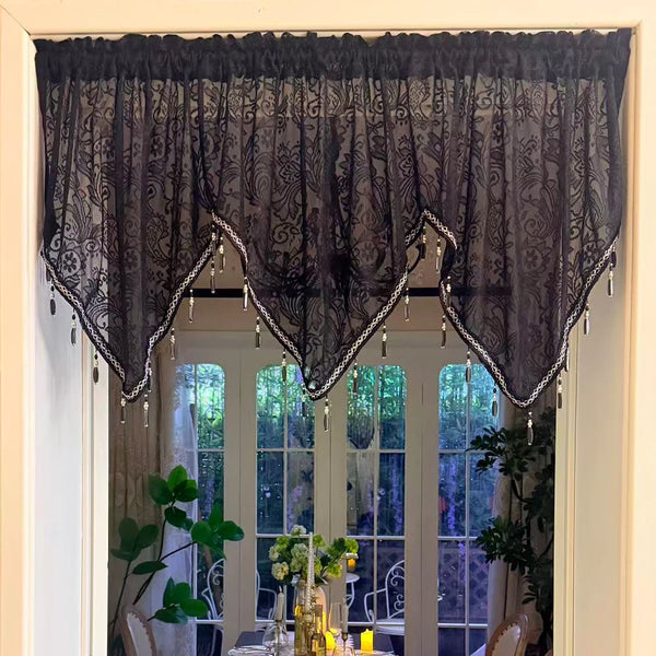 Elegant black lace curtain valance with silver fringe hanging over a glass door.