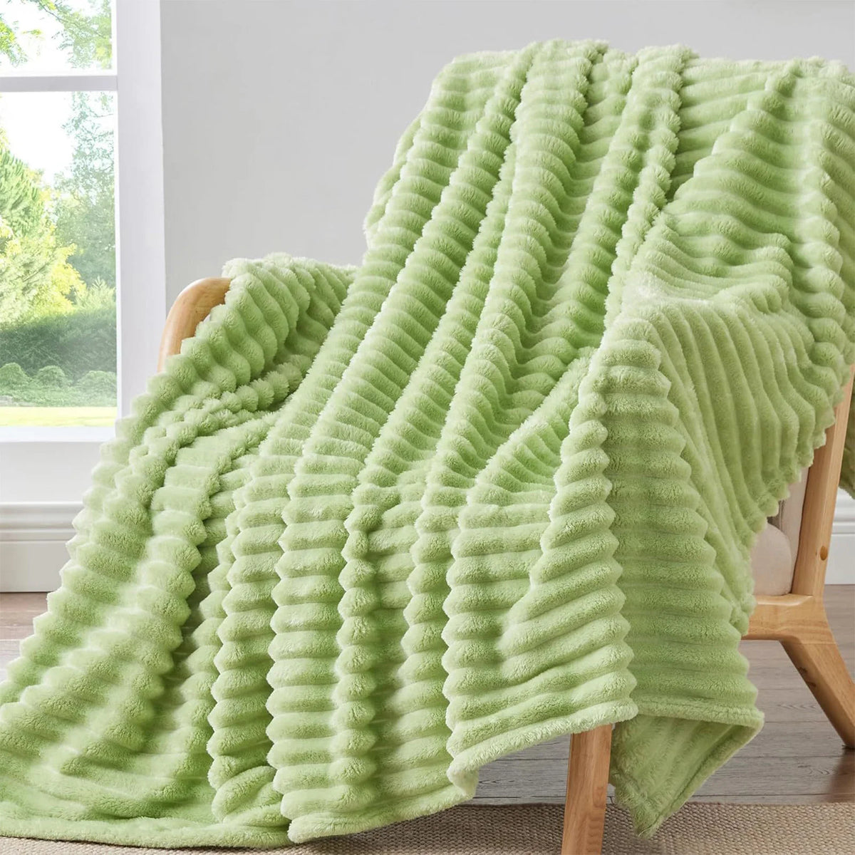 A light green, vertically ribbed flannel throw blanket draped over a wooden chair.