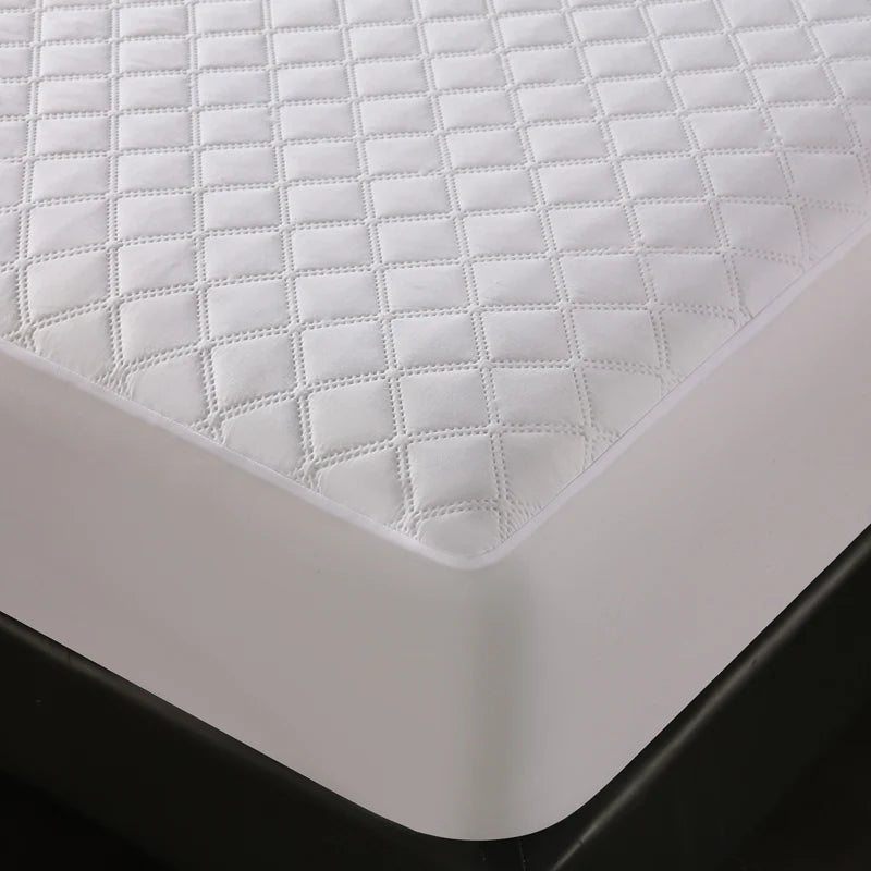 White waterproof quilted mattress protector placed on a black surface.
