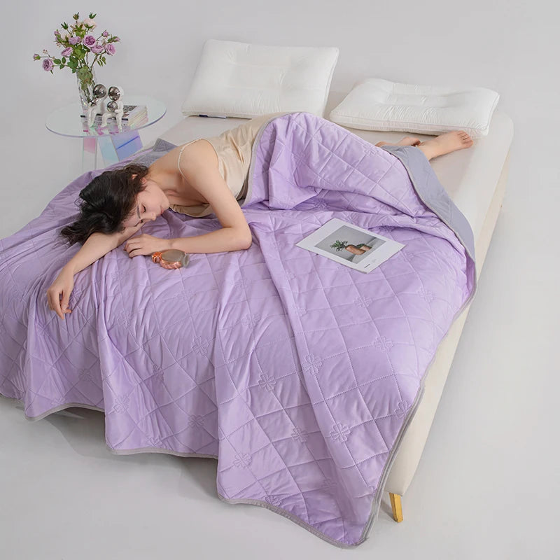 A person is lying down under a purple breathable cooling blanket on a white surface.