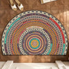 A boho half-round non-slip area rug with concentric circular patterns in earthy and vibrant colors mounted on a wooden wall.