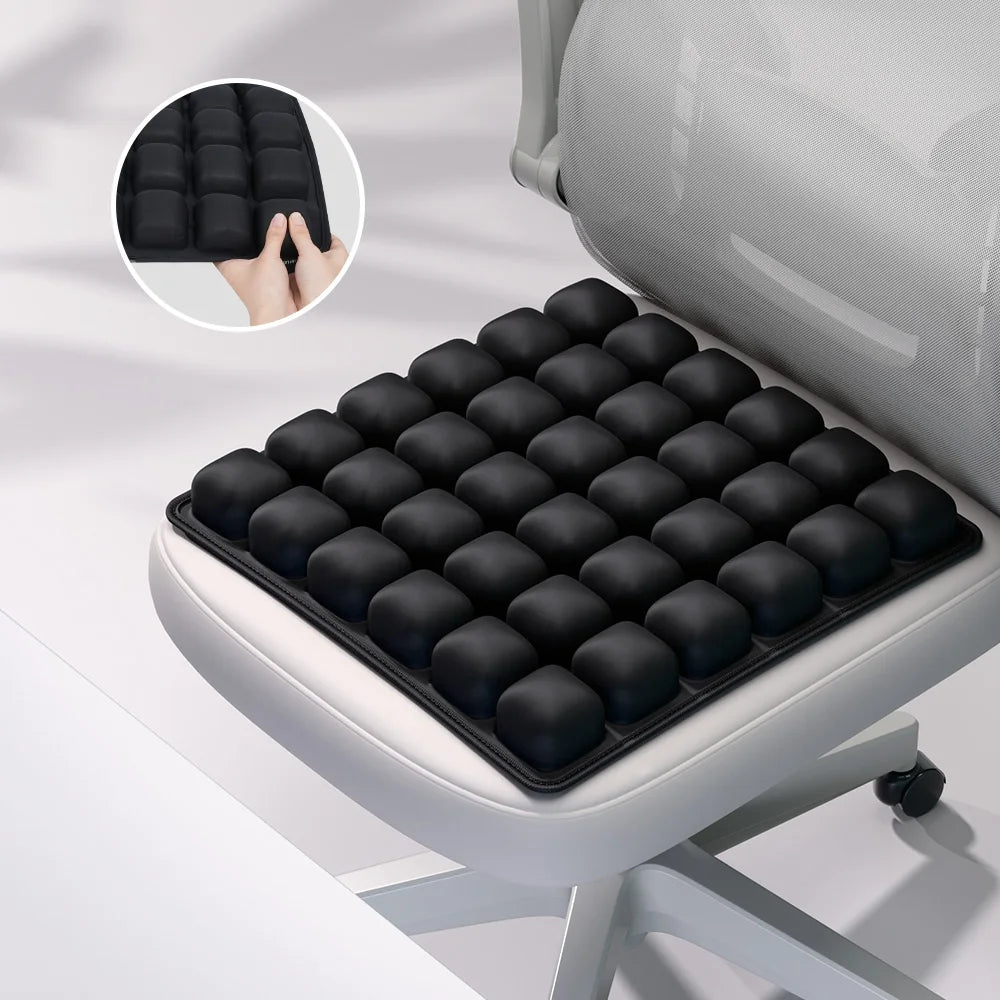 A black adjustable press-to-inflate seat cushion is shown being placed on a light gray chair seat.