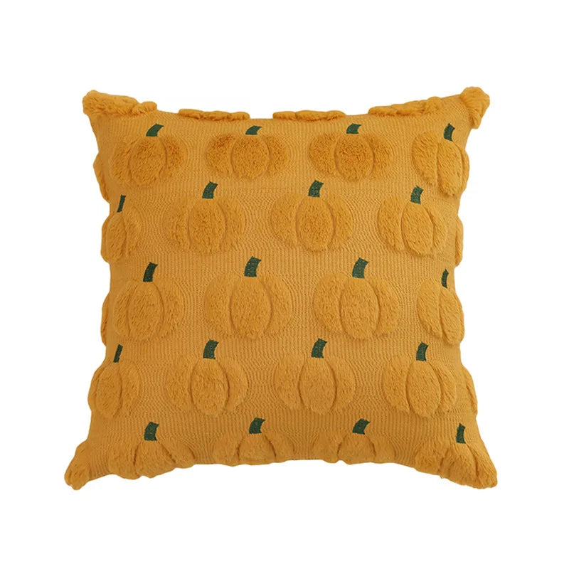 A square throw pillow covered in orange fabric featuring a repeating pattern of small green pumpkin shapes.