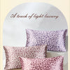 A stack of pink leopard print silk pillowcases displayed on a white surface.