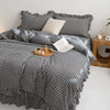 A plaid duvet cover set featuring black and white gingham fabric with a matching pillow and blanket on a bed.