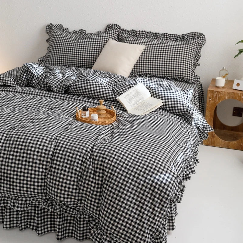 A plaid duvet cover set featuring black and white gingham fabric with a matching pillow and blanket on a bed.