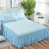 Light blue princess lace bed skirt set with white bedding and a large green plant in a bright room.