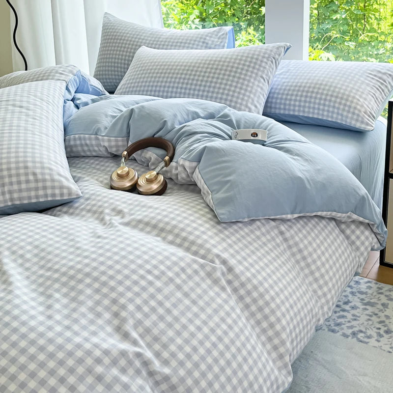 A light blue and gray striped checkered duvet cover set displayed on a bed with white curtains.