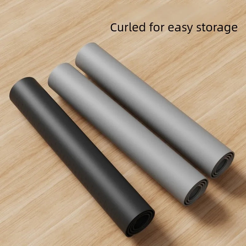 Three rolled heat-resistant silicone stove top cover mats lying on a wooden surface.