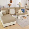 A beige jacquard elastic sofa cushion slipcover on a light-colored sofa with decorative pillows and a white dog.