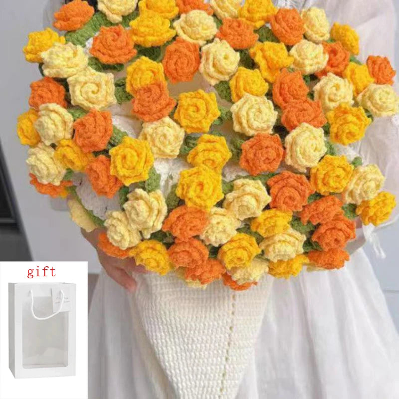 A bouquet of handmade rose crochet flowers in orange and yellow colors held by a person, with a gift bag visible.