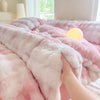 A pink cozy rabbit fleece duvet cover is draped on a bed, with a hand touching the fluffy material.