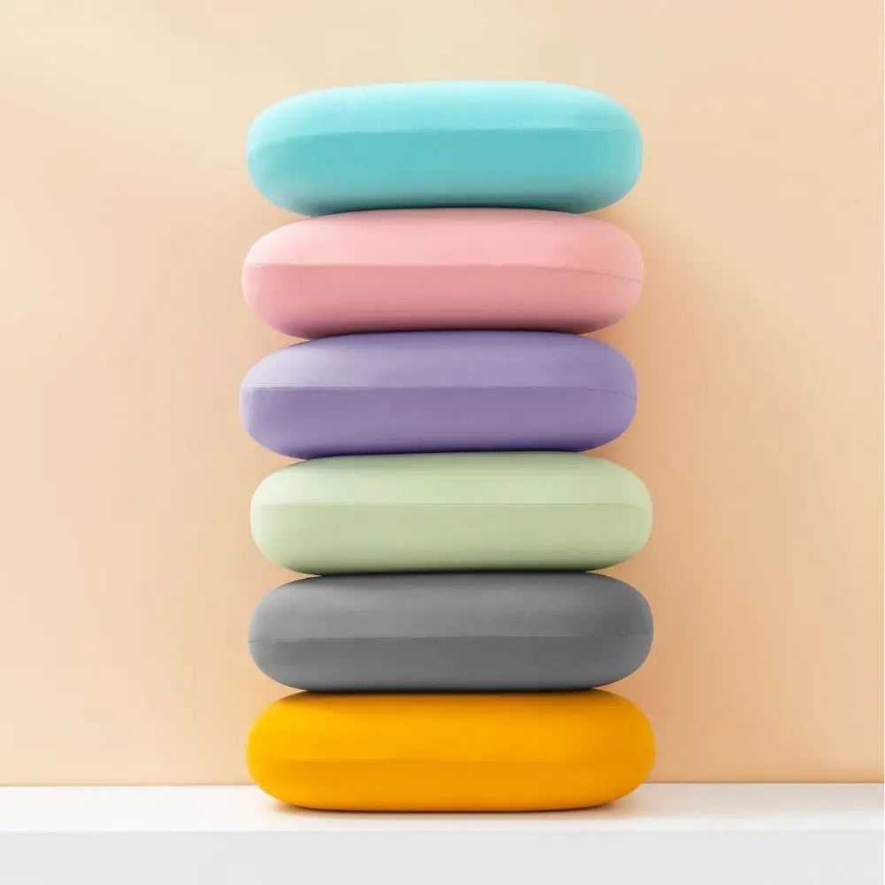 A stack of multi-function memory foam neck and travel pillows in pastel colors, arranged vertically on a white shelf.