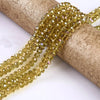 A strand of faceted round glass beads in a golden yellow color is unwrapped on a roll.
