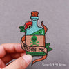 An embroidered patch depicting a green bottle with a red flower and a label that reads Poison Me