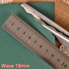 Stainless steel pinking shears shown next to a ruler on a green surface.