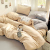 A beige cotton bed linen set with a duvet and pillows is displayed on a light gray bed.